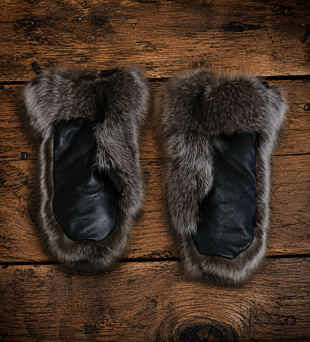 Luxury Canadian raccoon fur mittens in natural grey and black tones with a soft, full fur texture, displayed on a light neutral background. Handcrafted winter mittens offering exceptional warmth and timeless elegance.
