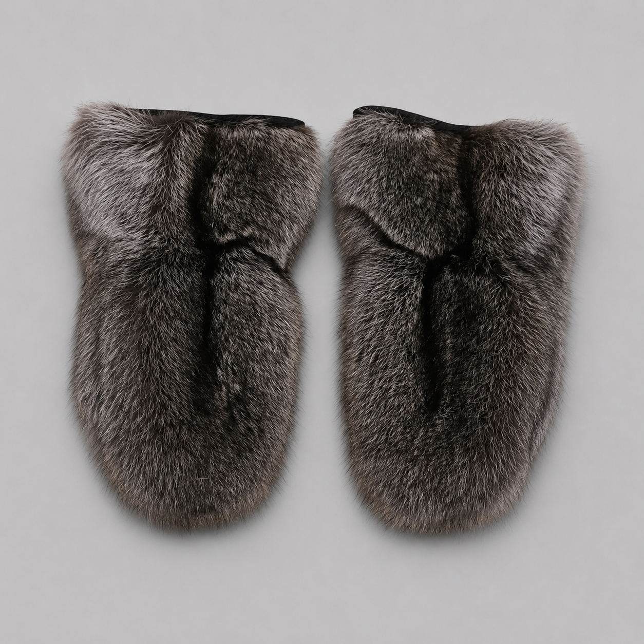 Luxury Canadian raccoon fur mittens in natural grey and black tones with a soft, full fur texture, displayed on a light neutral background. Handcrafted winter mittens offering exceptional warmth and timeless elegance.